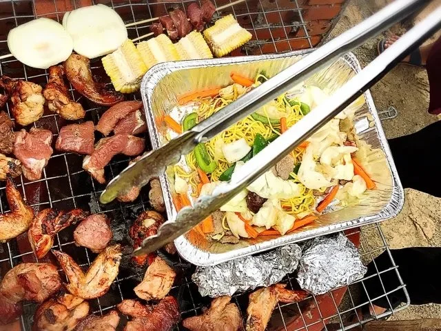 バーベキューの炭火グリルで肉・野菜・焼きそばを同時に焼いている様子