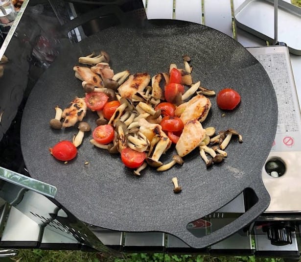マルチグリドルで鶏肉・きのこ・トマトを炒めているキャンプシーン
