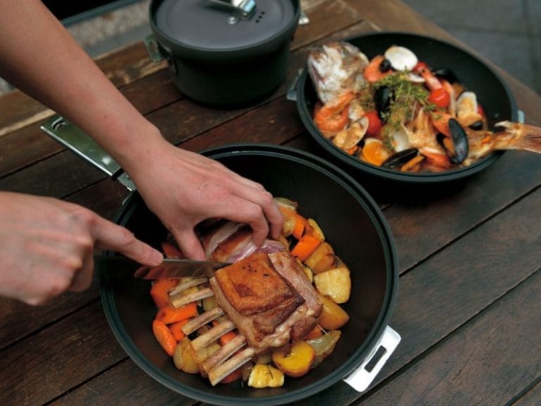 キャンプ用クッカーで肉料理を調理している様子