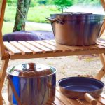 木製ラックに並べられたキャンプ用クッカーセットの写真。自然の中で料理を楽しむアウトドアの雰囲気が伝わる一枚。