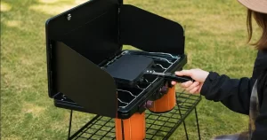 キャンプ用バーナーの上でホットサンドメーカーを使っている女性の様子