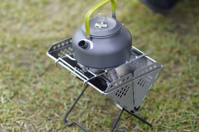 焚き火スタンドの上でお湯を沸かす小型キャンプケトル グリーンの持ち手付き