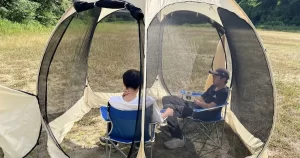 ポップアップリビングのメッシュ全開状態で2人がチェアでくつろいでいる様子