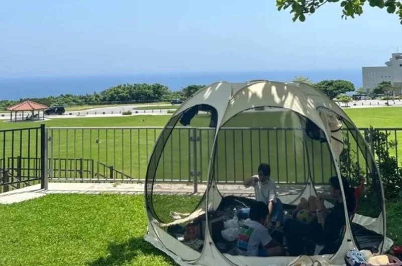海が見える公園でポップアップリビングを使っている家族の様子