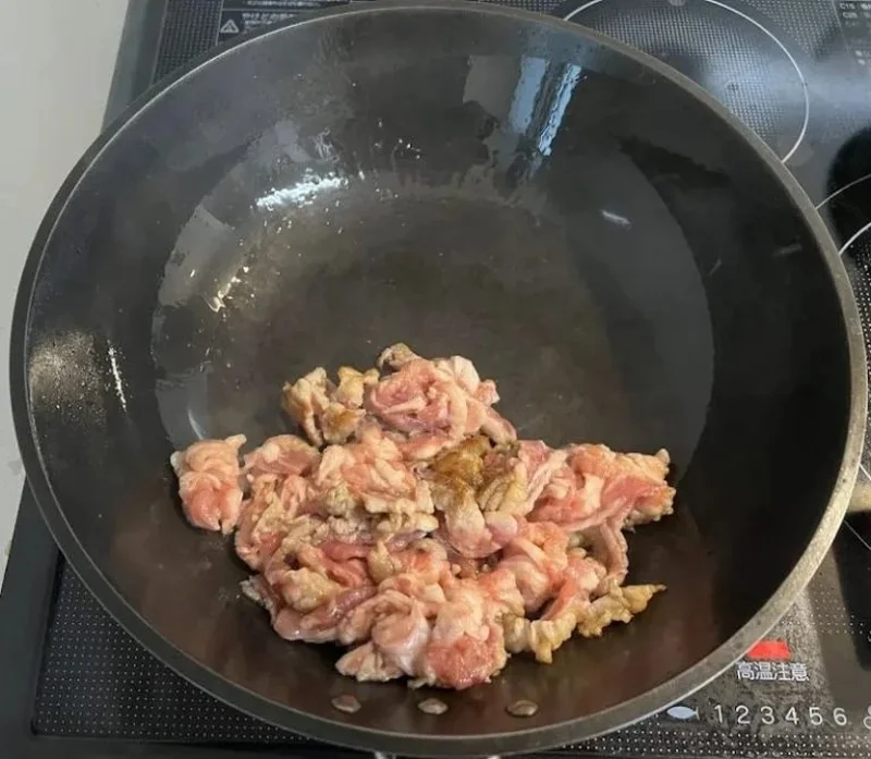 鉄フライパンで豚肉を炒めている様子