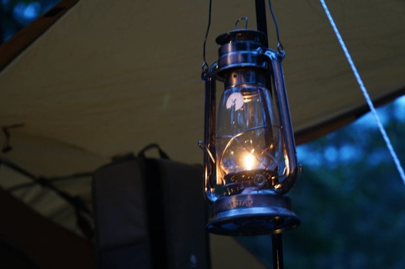 夕暮れのキャンプサイトで吊るされたランタンの灯り