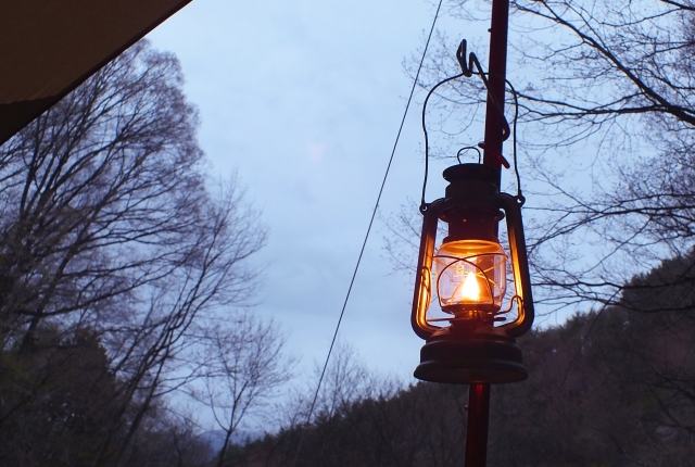 夕暮れのキャンプサイトで灯るランタン